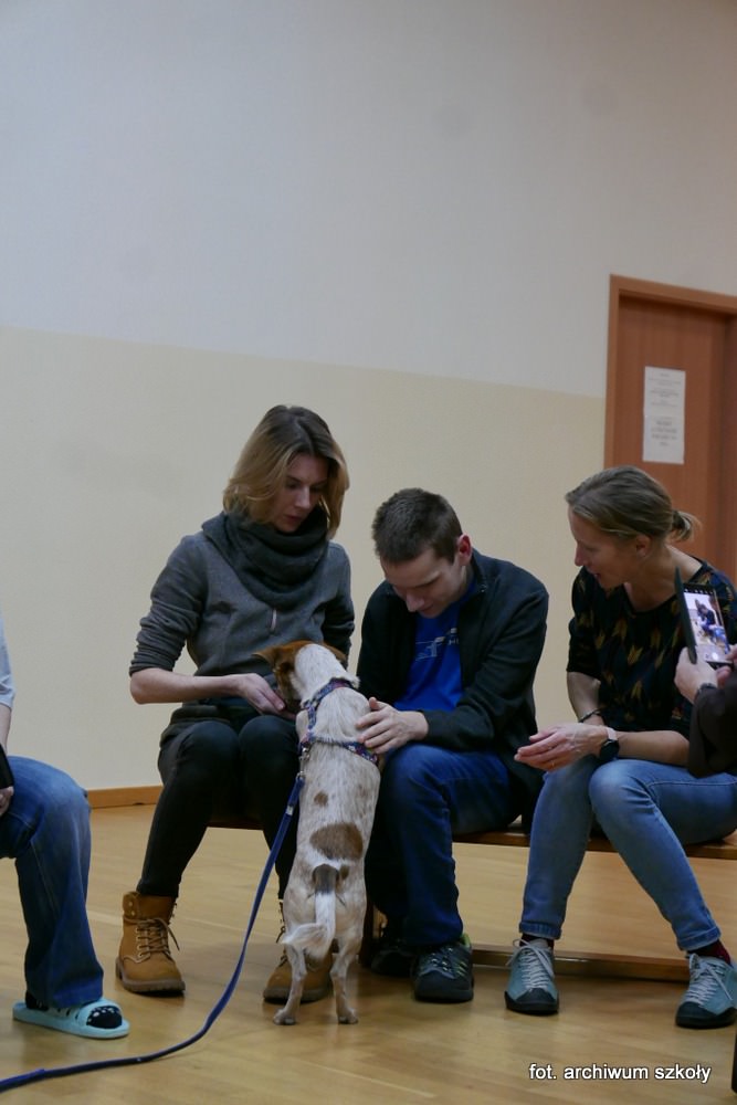 Uczeń z nauczycielką głaszcze psa.