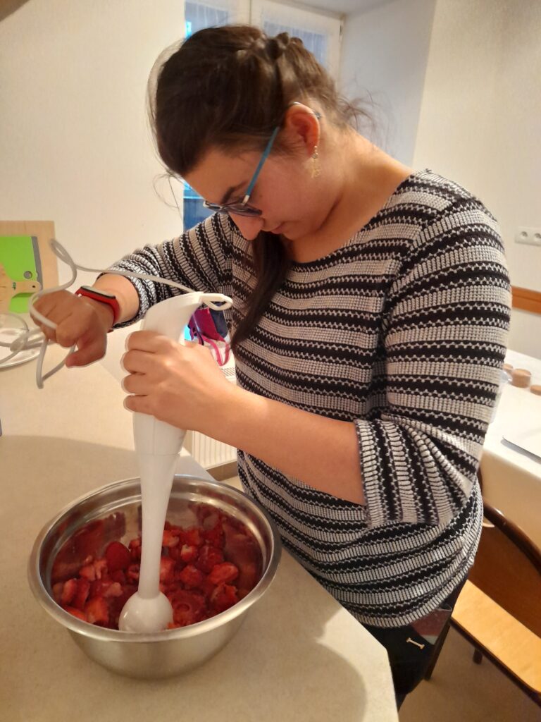 Uczennica blenderem miksuje truskawki.