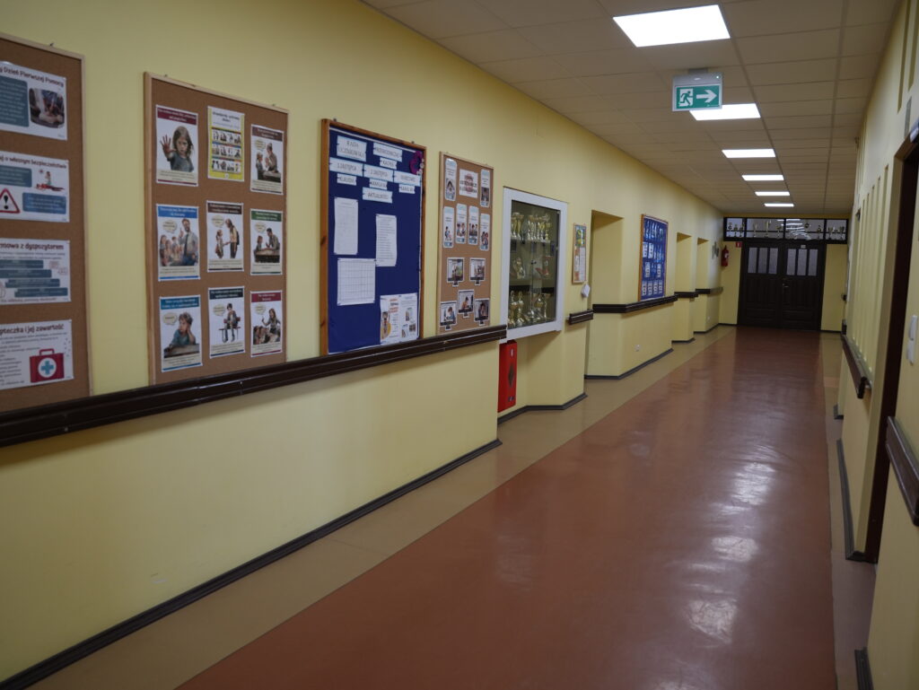 Szkolny korytarz z tablicami informacyjnymi.