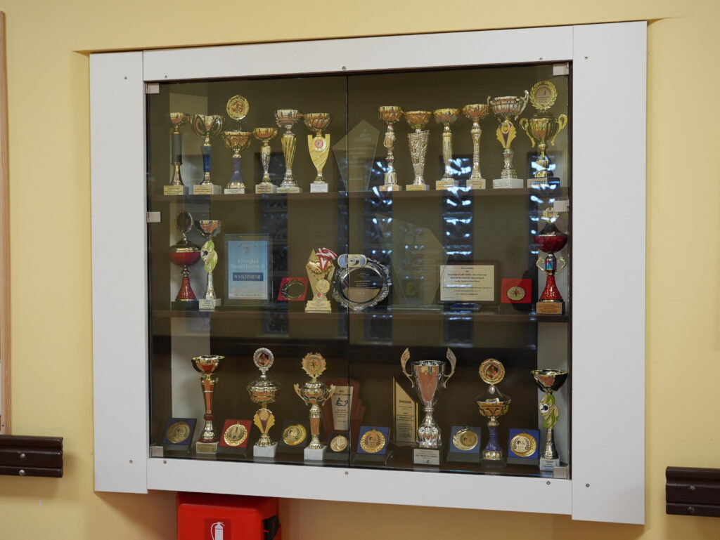 Gablota szkolna z pucharami i medalami z zawodów sportowych.