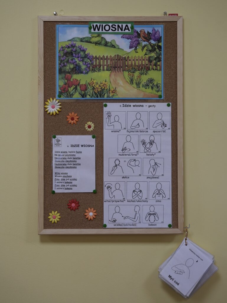 Tablica korkowa z obrazkiem wiosny i wierszem "Idzie Wiosna" z symbolami makatonu