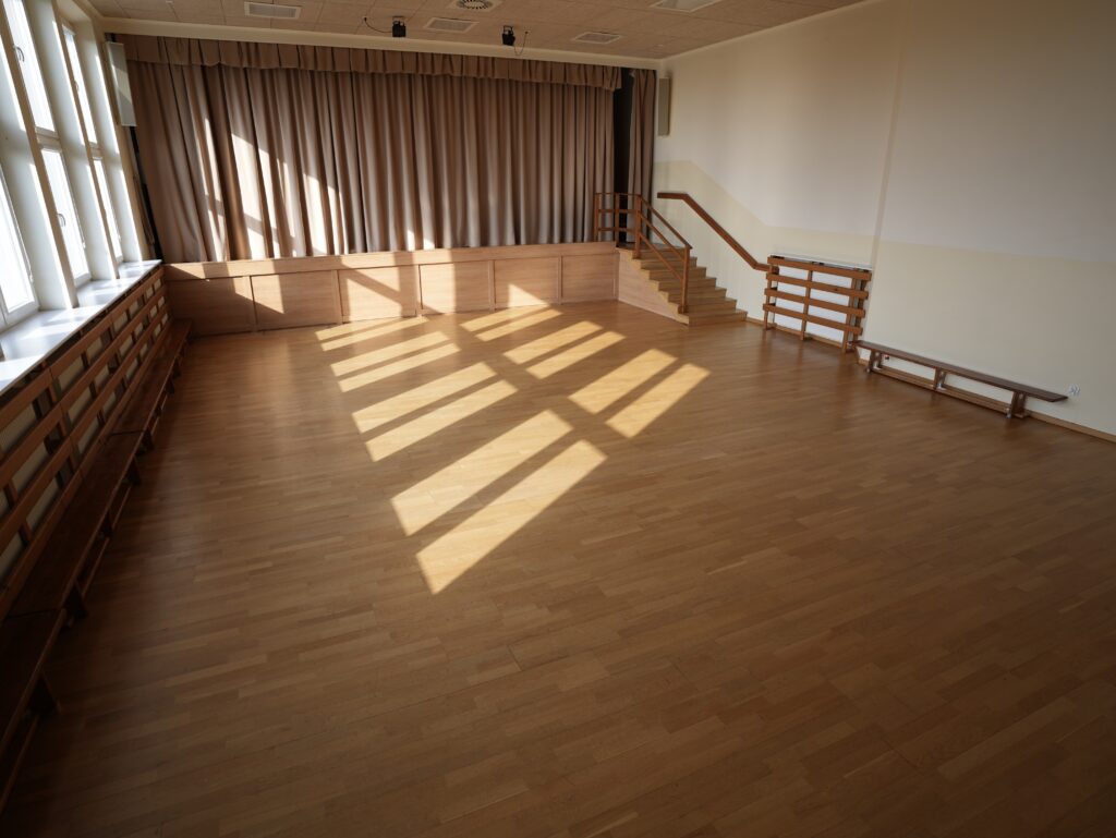 Sala gimnastyczna ze sceną, która jest zasłonięta kotarami. Po prawej stronie na scenę prowadzą schody.