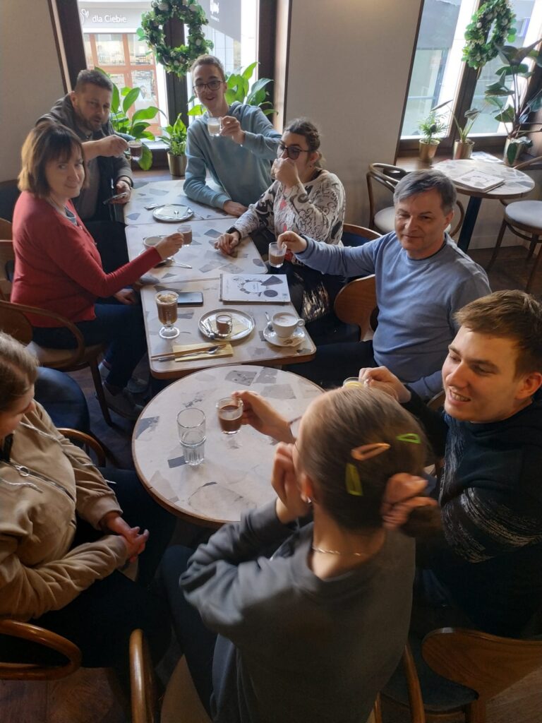 Nauczyciele i uczniowie siedzą w restauracji przy stoliku pijąc czekoladę.