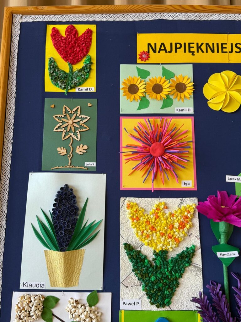 Tablica z pracami dzieci przedstawiającymi kwiaty, wykonanymi z różnych materiałów, m.in. papieru i plasteliny.