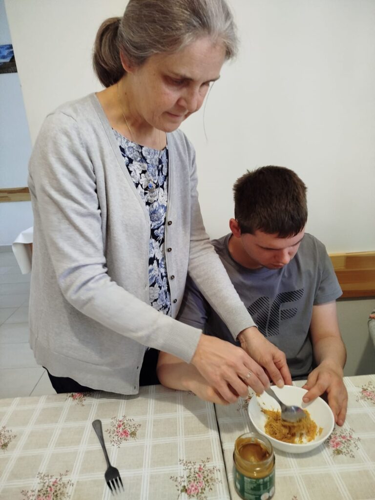 Chłopiec razem z nauczycielkom przekłada masę pistacjową ze słoika do miski.