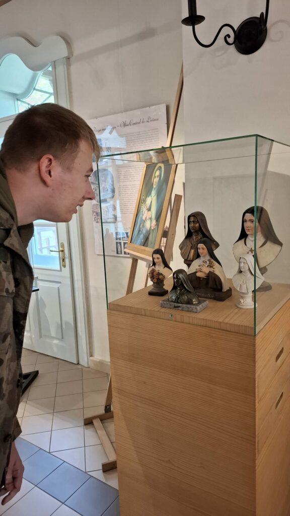 Mężczyzna ogląda z bliska gablotę z figurkami św. Teresy.