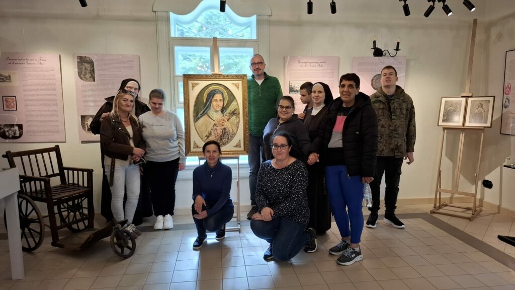 Grupa osób pozuje razem w muzeum przed obrazem świętej Teresy. w tle widoczne są plansze z opisami i stare eksponaty.