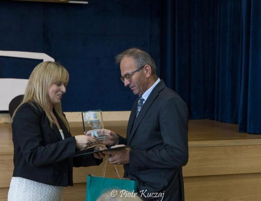 Burmistrz Rabki- Zdrój odbiera statuetkę i pamiątkowy dyplom z rak młodej kobiety. 