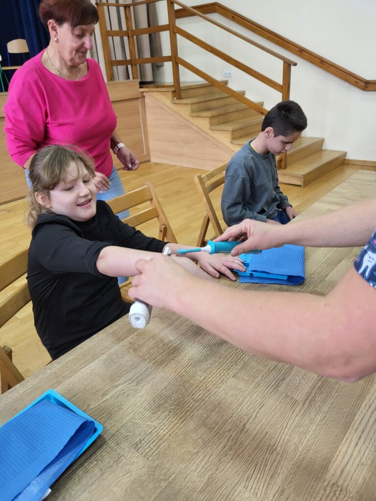 Dziewczynka sprawdza na ręce ruchy szczoteczki elektrycznej i sonicznej.