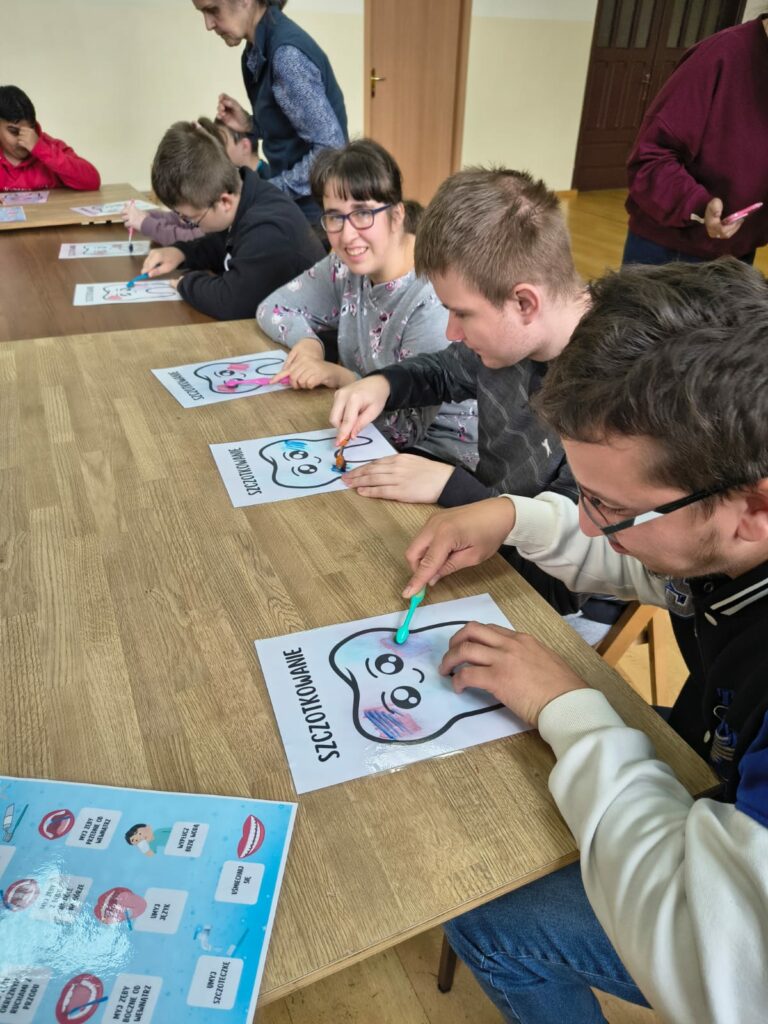Grupa osób na warsztatach uczy się prawidłowo szczotkować zęby.