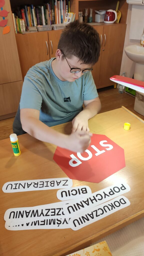 Młody mężczyzna nakleja na na czerwony znak wyraz stop.