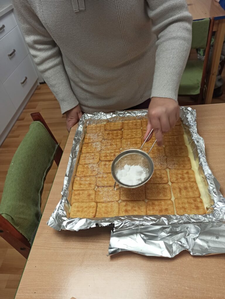 Posypywanie ciasta cukrem pudrem.