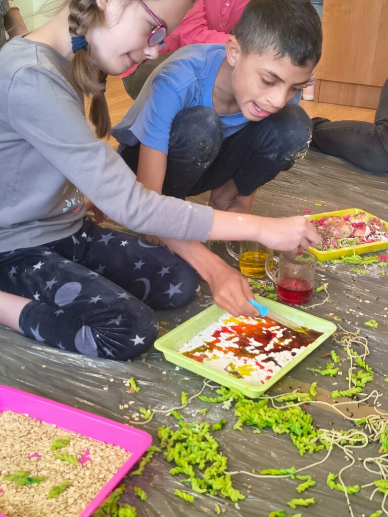 Dziewczynka i chłopiec barwią na różne kolory jesienne makarony.