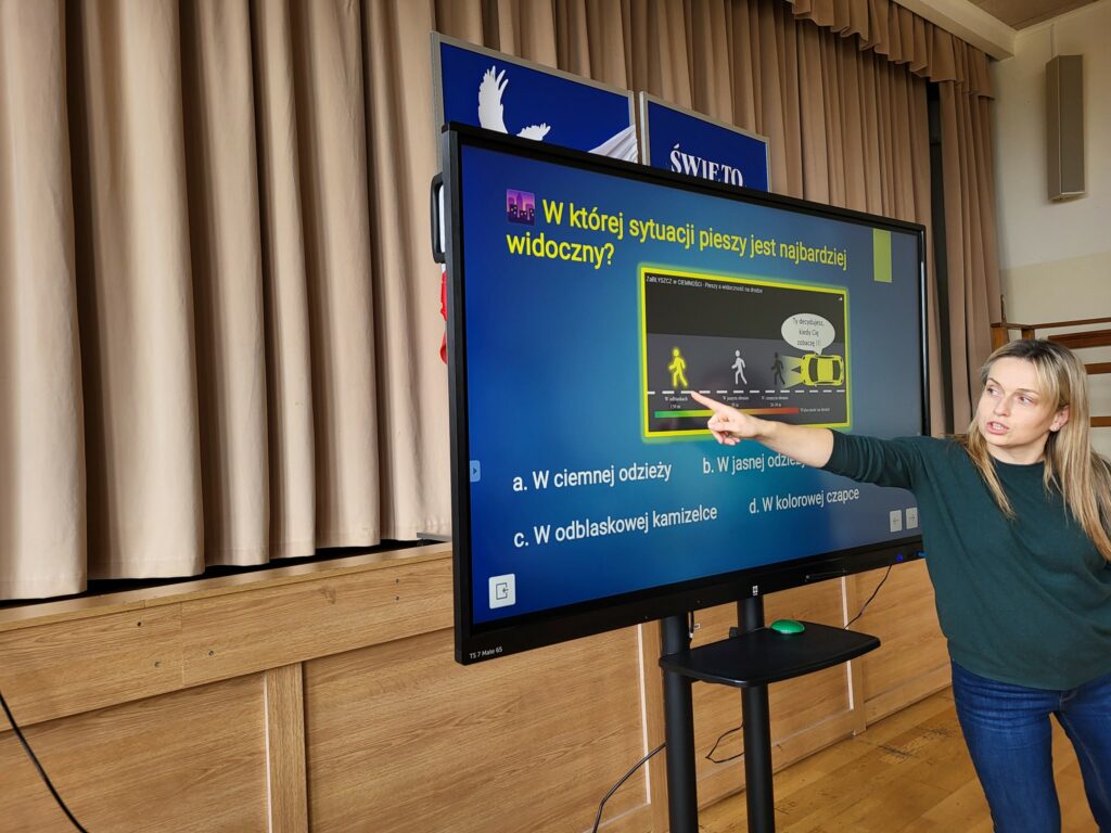 Kobieta objaśnia obrazek wyświetlony na urządzeniu multimedialnym.