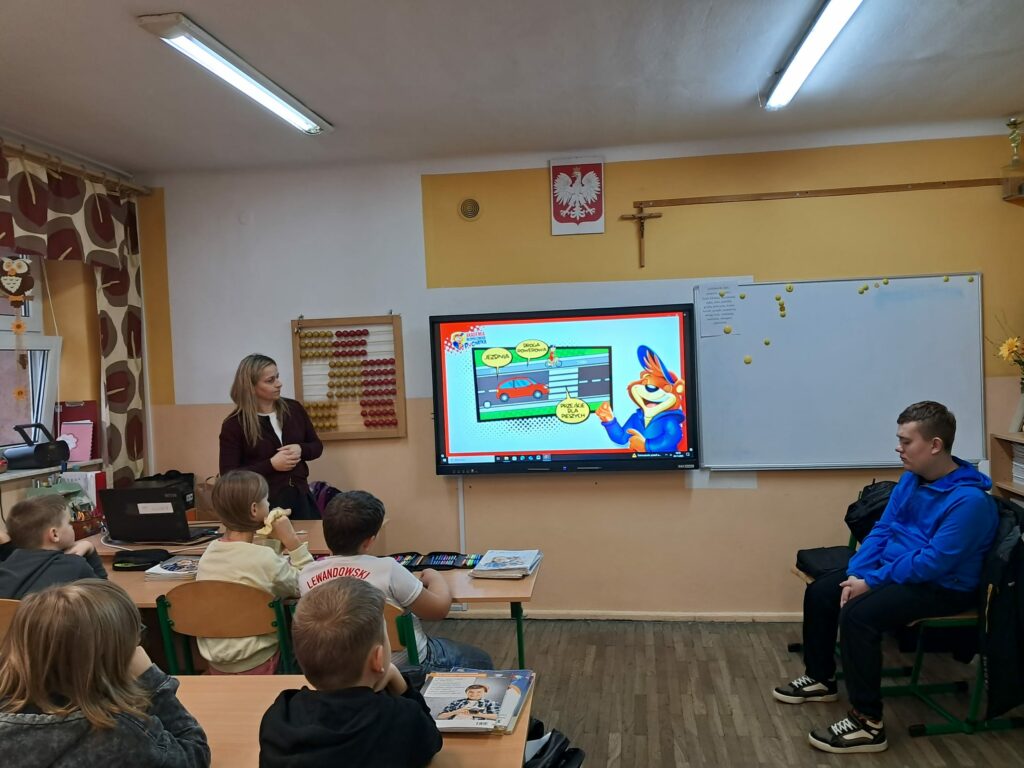 Dzieci oglądają w klasie film edukacyjny o bezpieczeństwie na drodze.