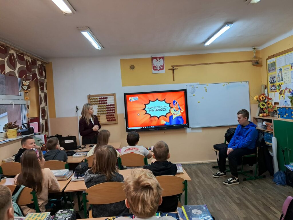 Kontynuacja poprzedniego zdjęcia. Grupa dzieci ogląda film wyświetlany na urządzeniu multimedialnym.