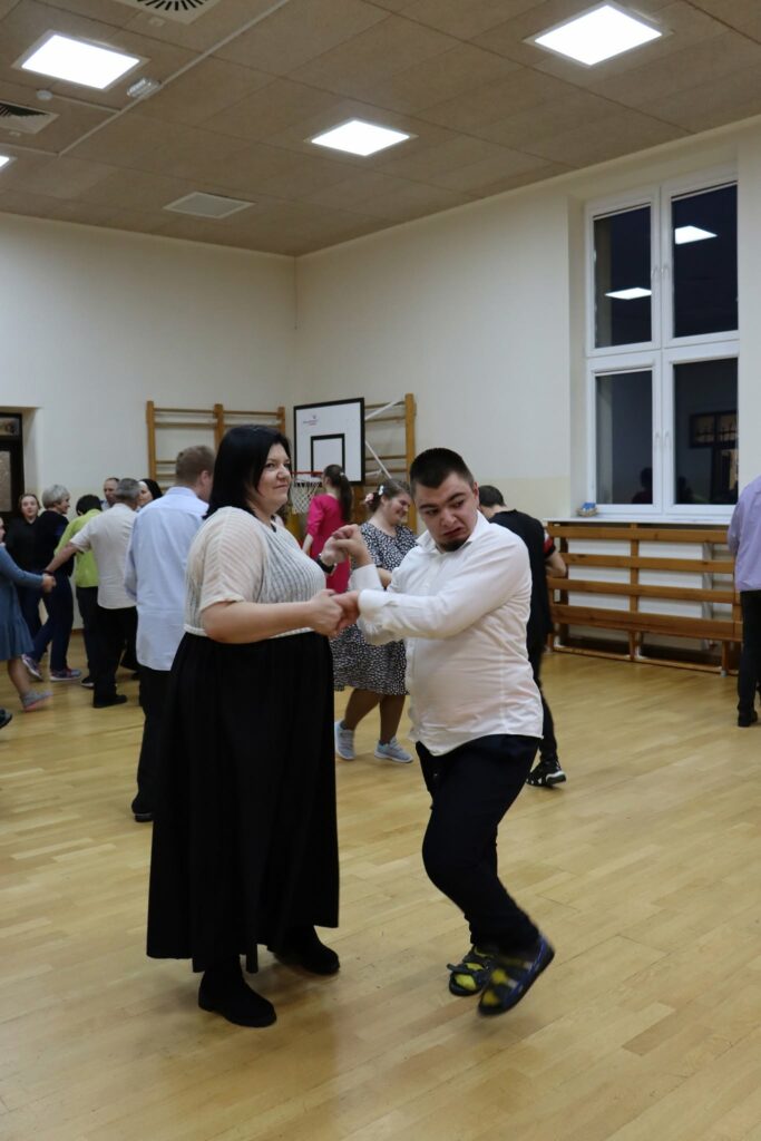 Kobieta tańczy z młodym mężczyzną na zabawie tanecznej.