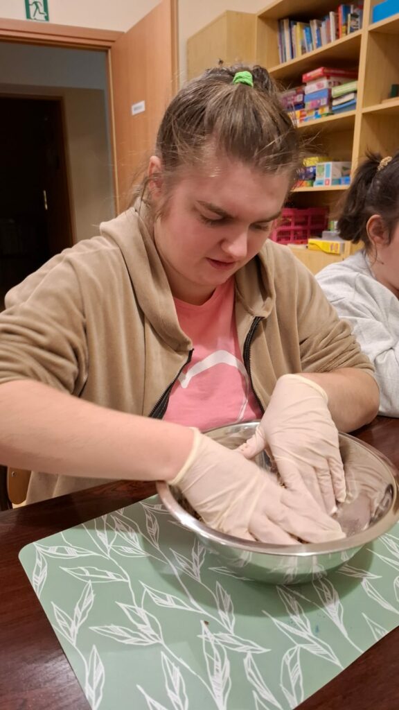 Młoda kobieta w jednorazowych rękawiczkach trzyma ręce w misce.