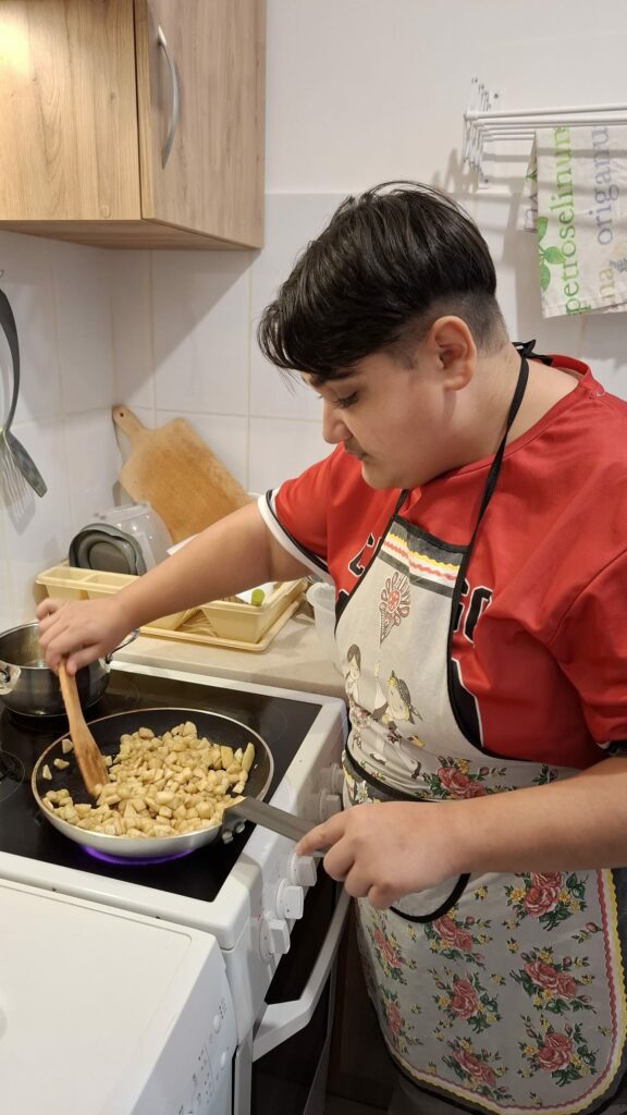 Młody mężczyzna podsmaża na patelni pokrojone jabłka.