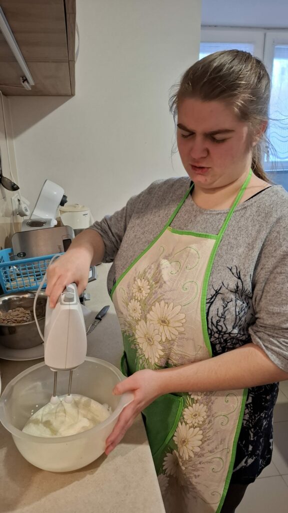 Kobieta ubija mikserem pianę z białek w misce.