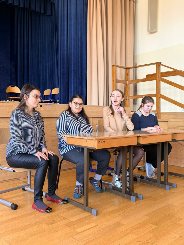 Grupa osób siedzi przy stolikach uśmiechając się .