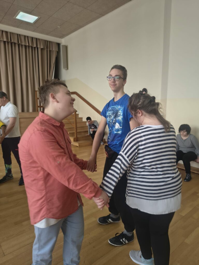 Dziewczynka i dwóch chłopców trzymają się za ręce podczas tańca.