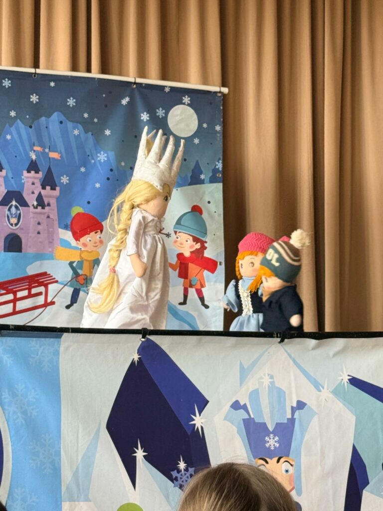 Kukiełki dzieci rozmawiają z postacią Królowej Śniegu podczas przedstawienia.