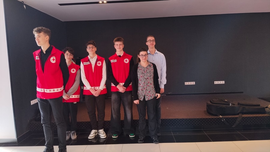 Grupa wolontariuszy w czerwonych kamizelkach pozująca do wspólnego zdjęcia.