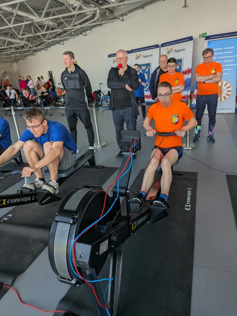 Dwaj zawodnicy na ergometrach wioślarskich w trakcie zawodów.
