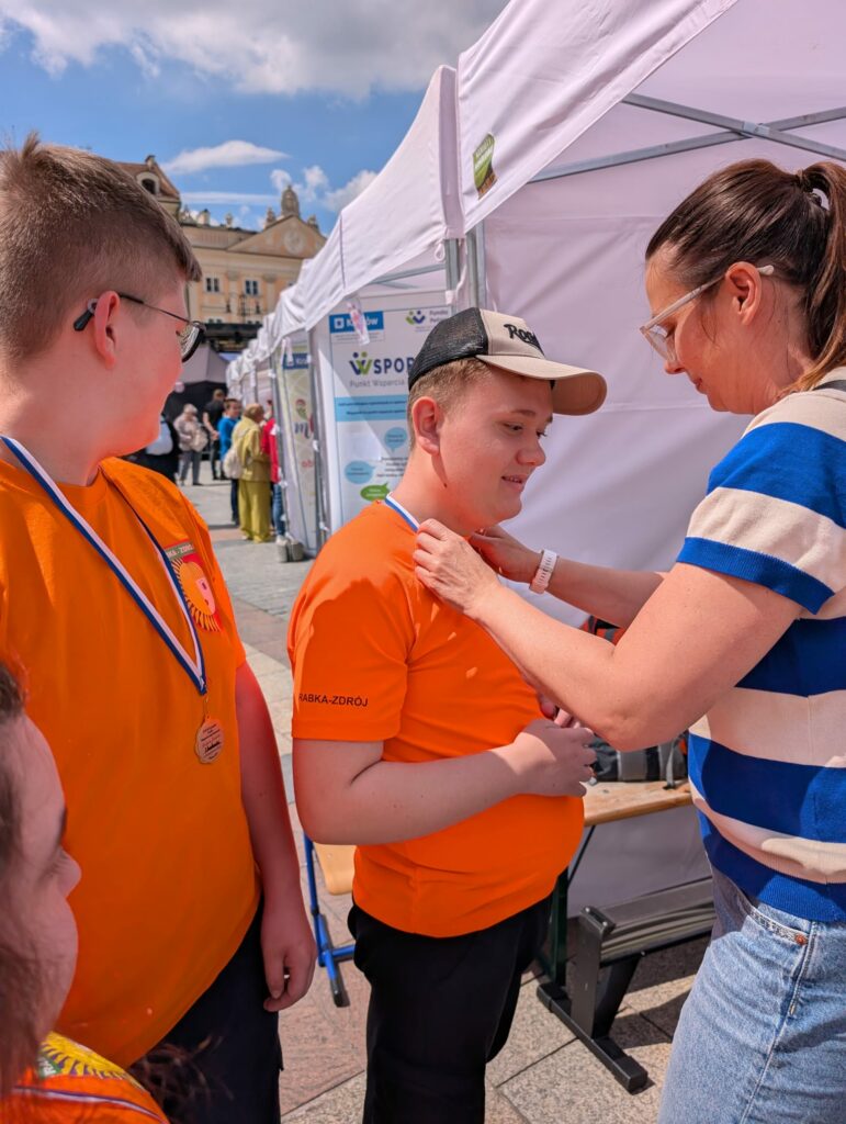 Kobieta wręcza medal uczestnikom zawodów wioślarskich.