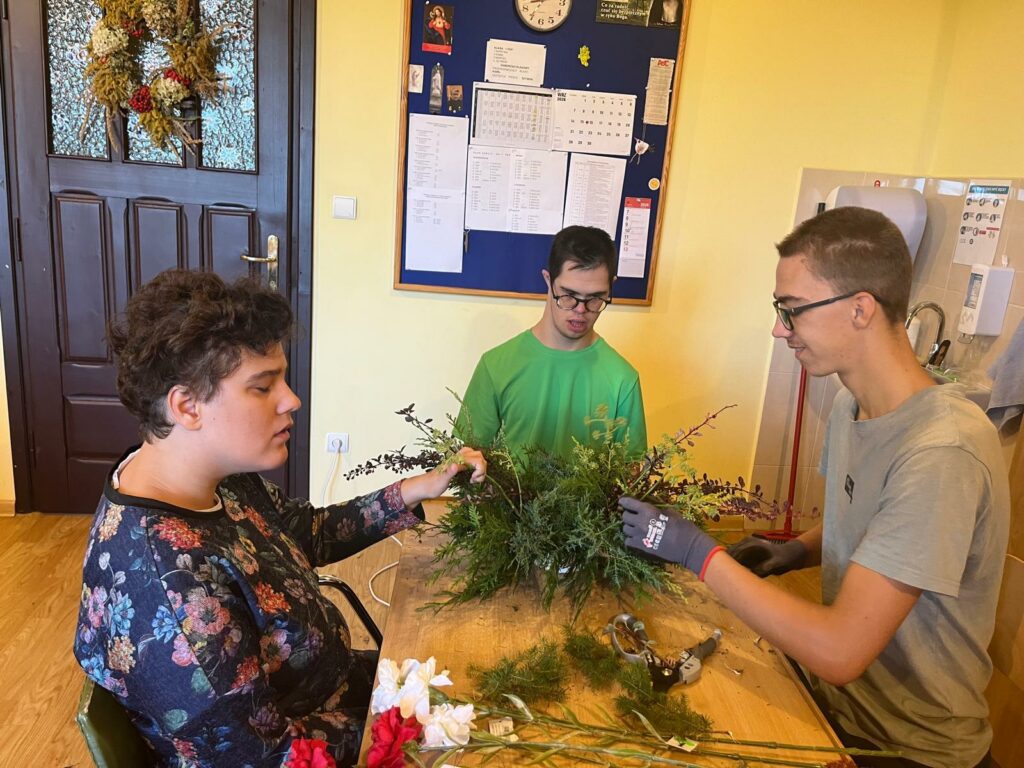 Uczniowie podczas zajęć florystycznych przygotowują kompozycję z jesiennych roślin i gałązek.