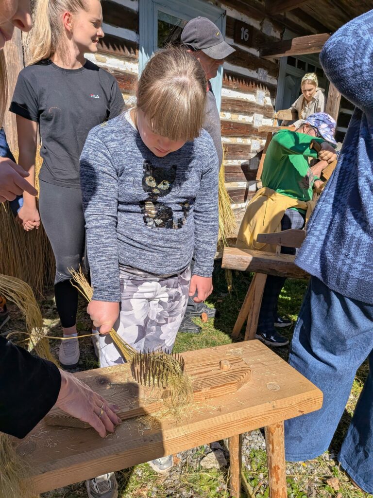 Dziewczynka podczas pracy na tradycyjnym narzędziu do obróbki lnu.
